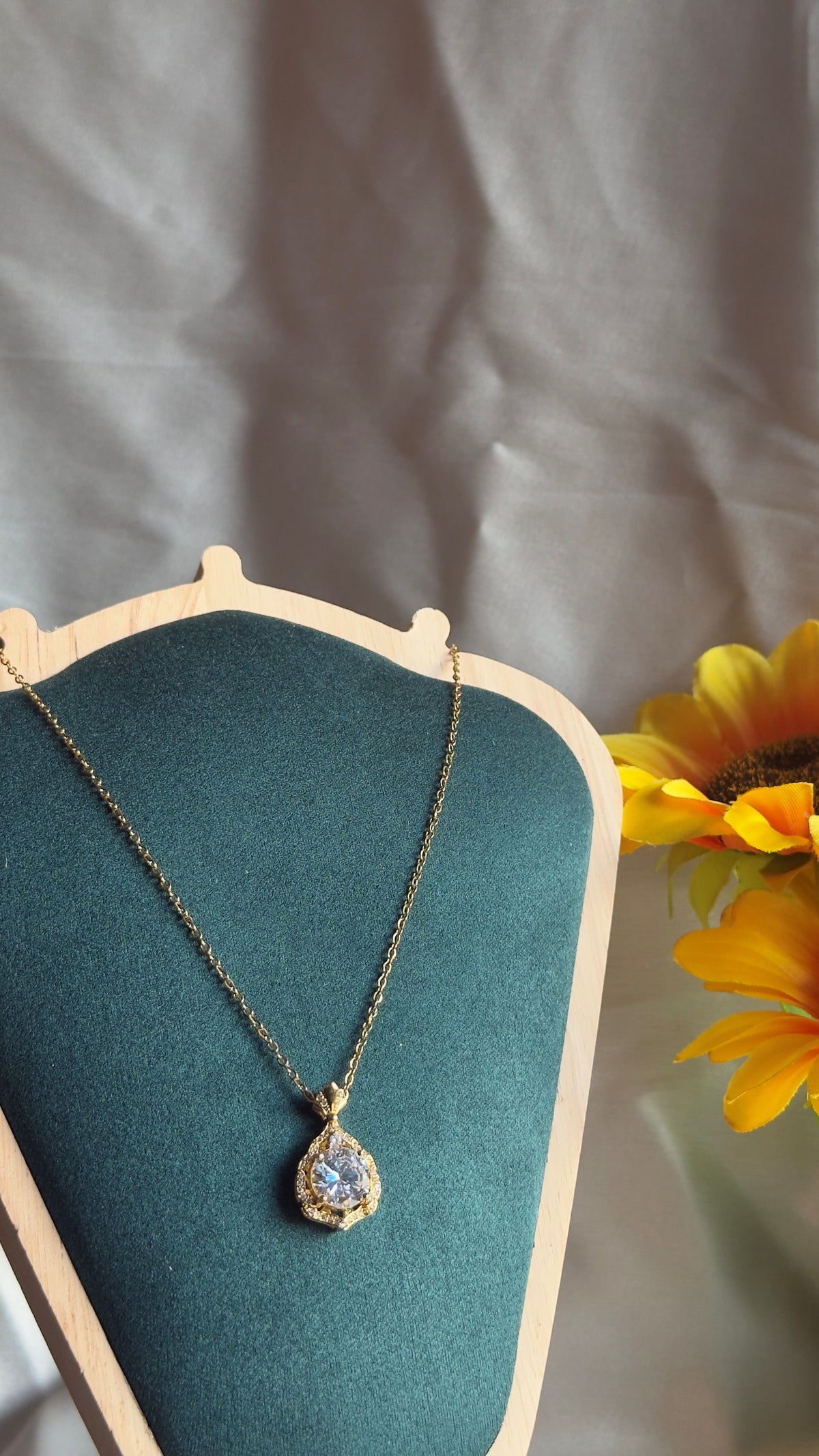 Gold diamond pendant necklace on teal velvet display